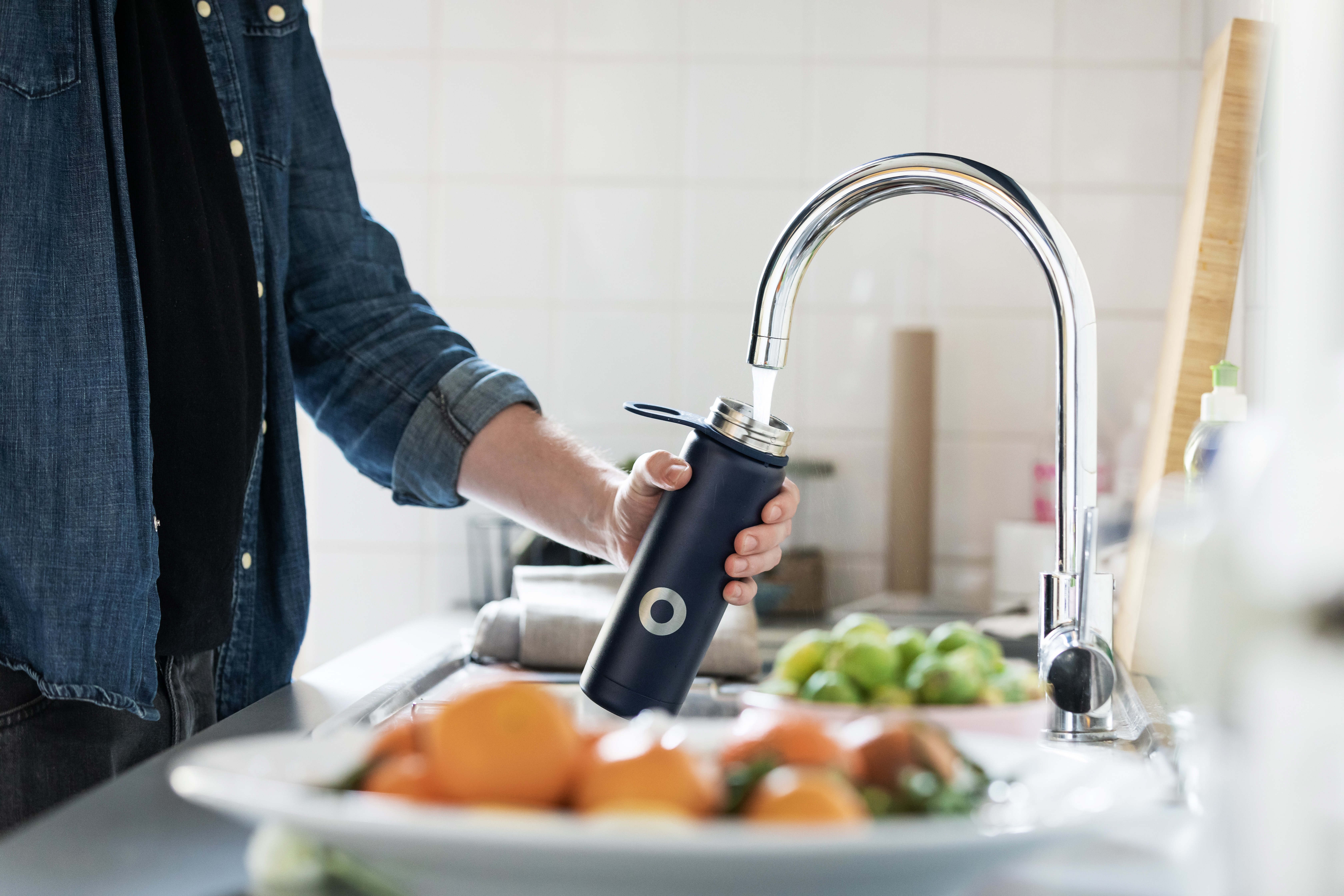 Man filling up water bottle from kicthen sink