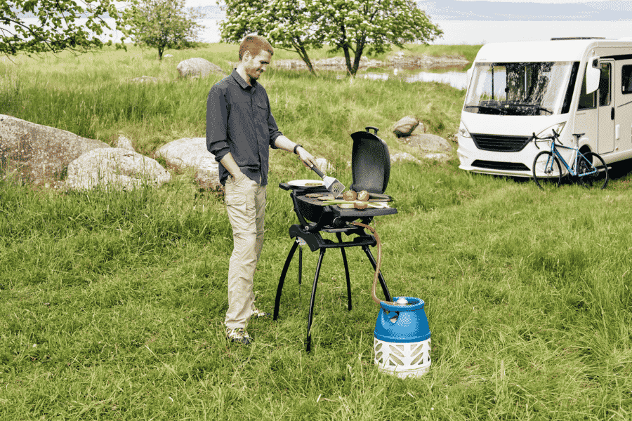 man grilling wih propane at campsite